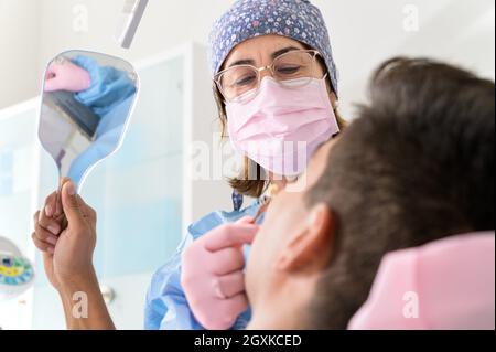 Patient schauende Zähne im Spiegel in der Zahnklinik. Hochwertige Fotos. Stockfoto