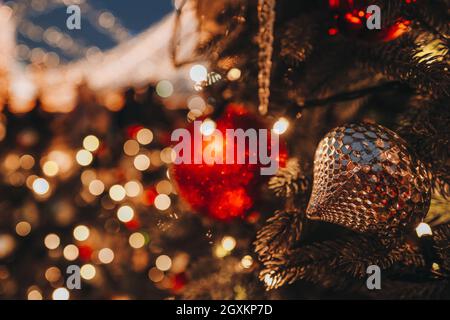 Weihnachtsspielzeug rote Goldkugeln hängen auf dem Weihnachtsbaum mit verschwommenen goldenen festlichen Bokeh Lichter auf dem Hintergrund. Frohe Weihnachten und ein glückliches neues Jahr Stockfoto