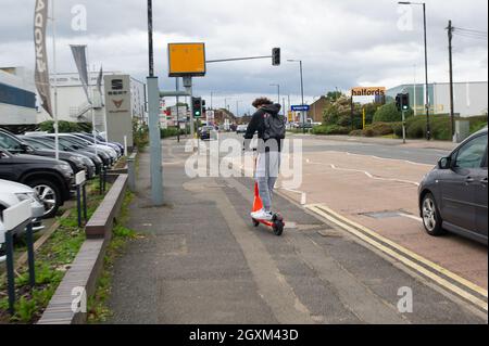 Slough, Großbritannien. Oktober 2021. Ein junger Mann fährt mit einem gemieteten E-Scooter auf dem Bürgersteig in Slough. Quelle: Maureen McLean/Alamy Stockfoto