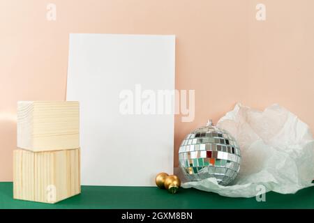 Stillleben mit Holzwürfeln und Diskokugel, die Sonneneruptionen vor smaragdgrünem Hintergrund reflektiert Stockfoto