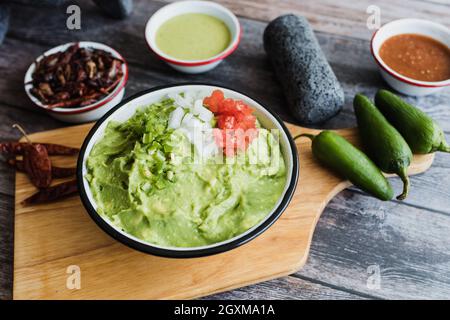 Schüssel mit Guacamole neben frischen Zutaten auf einem Holztisch in Mexiko Stockfoto