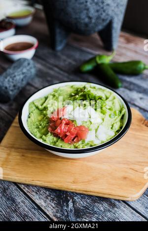 Schüssel mit Guacamole neben frischen Zutaten auf einem Holztisch in Mexiko Stockfoto