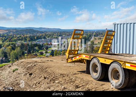 Ein Traktor-Anhänger parkt am Rande eines Schotterplatzes am Hang, bereit für ein neues Zuhause mit Blick auf die Städte Greenacres, Liberty Like, Spokane Washington Stockfoto