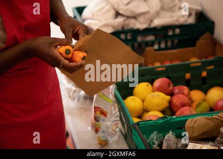 Ein nicht identifizierbarer Freiwilliger bei einer Lebensmittelbank, der Kisten mit gespendetem Essen sortiert, um sie für die Verteilung an Mitglieder der örtlichen Gemeinde in Not vorzubereiten. S Stockfoto