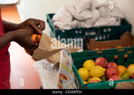 Ein nicht identifizierbarer Freiwilliger bei einer Lebensmittelbank, der Kisten mit gespendetem Essen sortiert, um sie für die Verteilung an Mitglieder der örtlichen Gemeinde in Not vorzubereiten. S Stockfoto