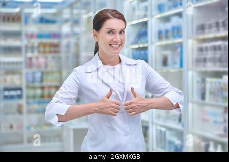 Fröhliche Apothekerin, die in der Apotheke steht Stockfoto