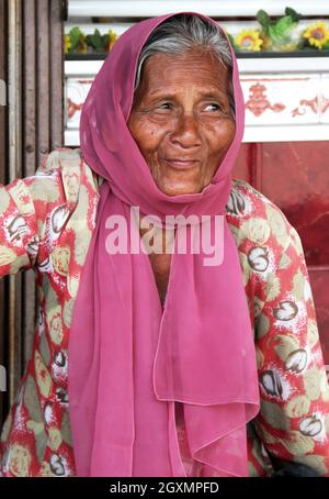 Eine schöne alte Frau in einem rosafarbenen Kleid mit einem rosa Hijab oder Kopftuch in Bukittinggi, West Sumatra, Indonesien. Stockfoto