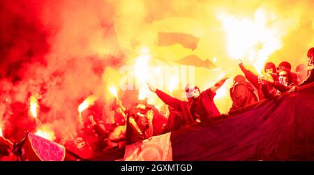 Fußball-Hooligans mit Maske halten Fackeln in Feuer, während Ihre Lieblingsmannschaft Unterstützung bei einem Spiel im Stadion Stockfoto