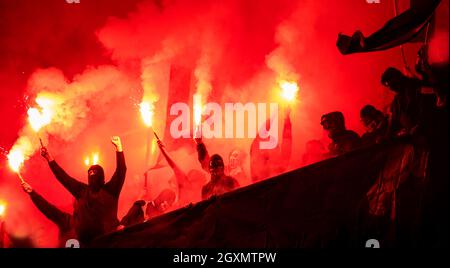Fußball-Hooligans mit Maske halten Fackeln in Feuer, während Ihre Lieblingsmannschaft Unterstützung bei einem Spiel im Stadion Stockfoto