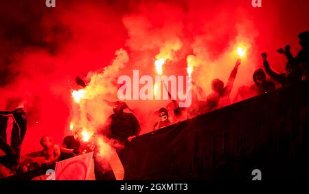 Fußball-Hooligans mit Maske halten Fackeln in Feuer, während Ihre Lieblingsmannschaft Unterstützung bei einem Spiel im Stadion Stockfoto
