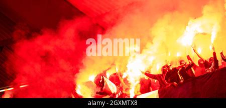 Fußball-Hooligans mit Maske halten Fackeln in Feuer, während Ihre Lieblingsmannschaft Unterstützung bei einem Spiel im Stadion Stockfoto