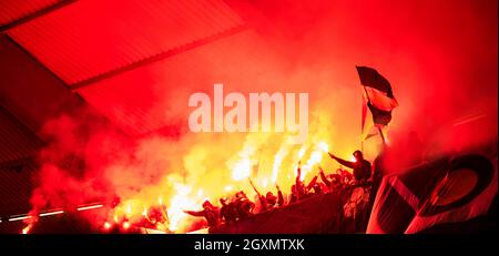 Fußball-Hooligans mit Maske halten Fackeln in Feuer, während Ihre Lieblingsmannschaft Unterstützung bei einem Spiel im Stadion Stockfoto