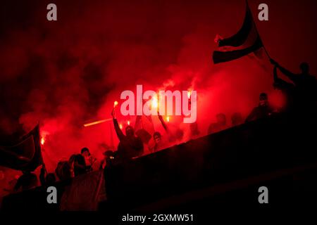 Fußball-Hooligans mit Maske halten Fackeln in Feuer, während Ihre Lieblingsmannschaft Unterstützung bei einem Spiel im Stadion Stockfoto