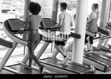 junge Leute Exercisinng Cardio am Laufband läuft Maschine im modernen Fitnessraum Stockfoto