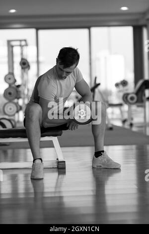 schönen jungen Mann mit Hanteln in einem Fitness-Studio trainieren Stockfoto