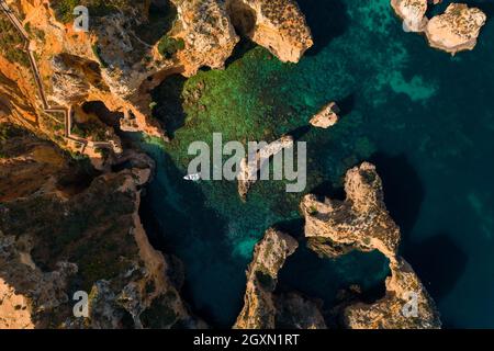 Ponta da Piedade, die berühmtesten touristischen Attraktionen Portugals. Luftaufnahme der Atlantikküste mit Klippenfelsen und Touristenboot an der Algarve Stockfoto
