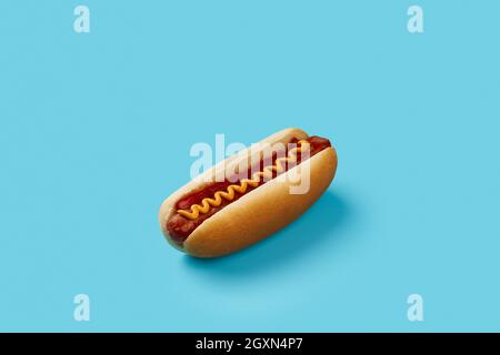 Klassischer Hot Dog mit Wurst, Ketchup und Senf auf blauem Hintergrund. Speisekarte für das Restaurant Stockfoto