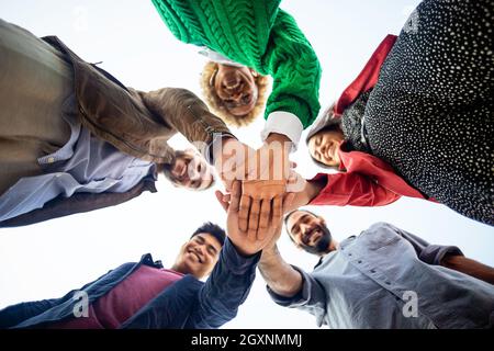 Vereinigte verschiedene glückliche junge Menschen, die Hände stapeln Stockfoto