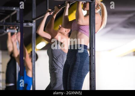 Gruppe junge muskulöse Athleten Zug tut ups auf der horizontalen Leiste als Teil der Cross Fitness Training Stockfoto