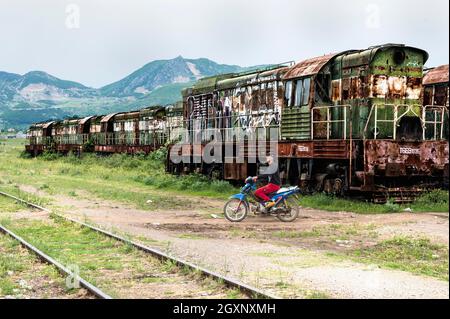 Motorradfahrer überqueren Bahngleise, ehemaliger Bahnhof Prrenjas, Albanien Stockfoto