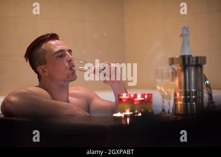 schöner junger Mann genießt, entspannen im Whirlpool mit Kerzen und Champagner im Luxus-Resort-spa Stockfoto