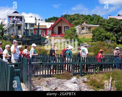 Neuseeländische Touristen machen sich auf den Weg durch das Whaka Village auf der Nordinsel in Rotorua. Das Dorf Maori existiert seit Jahrhunderten, und Touristen besuchen und werden im Laufe der Jahre Teil der Landschaft. Das Dorf liegt in der Vulkanzone Taupo und ist für seine geothermische Landschaft und Aktivitäten bekannt. Heiße Pools, Schlammbecken, Geysire und heiße Quellen gehören zu der einzigartigen Landschaft und sind ein Beispiel für nachhaltiges Leben, da sie mit der Erde leben, anstatt sie zu kontrollieren. Stockfoto
