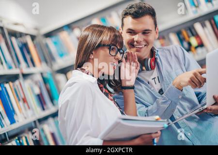 Zwei Schüler mit moderner Technik stehen in der Schulbibliothek Stockfoto