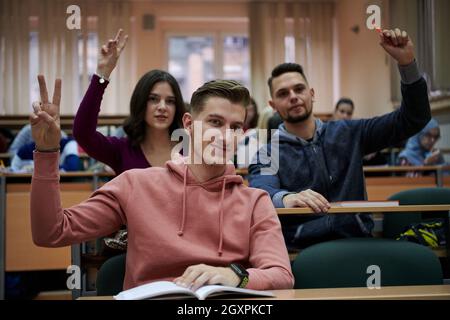 Im Klassenzimmer Multiethnische Studenten Hören Sie einem Dozenten zu und schreiben Sie in Notizbüchern. Intelligente junge Menschen studieren an der Hochschule. Stockfoto