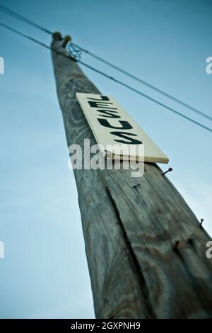 Telefonmast mit Nägeln und einem weißen Schild mit schwarzen Buchstaben, auf dem Jesus steht Stockfoto