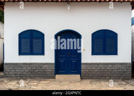 Weiße Wände und blaue Türen und Fenster, Vorderansicht des Pfarrhauses von Sant’Ana de Inconfidencia in Sebollas, Paraiba do Sul, Brasilien. Die Kirche und das Haus Stockfoto