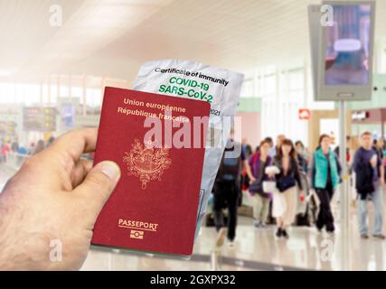 Hand mit französischem Pass und faltenem Coronavirus Covid 19-Immunitätszertifikat aus Papier. Verschwommener Flughafen im Hintergrund. Immunität gegen Covid Stockfoto