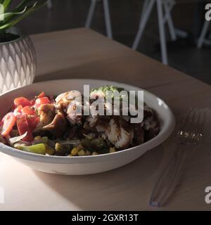 Schüssel mit frischem, gesundem Chicken Fajita-Salat mit Maisreis, gegrillten Paprika und Guacamole Stockfoto