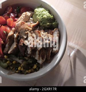 Schüssel mit frischem, gesundem Chicken Fajita-Salat mit Maisreis, gegrillten Paprika und Guacamole Stockfoto