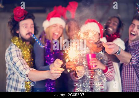 Multiethnische Gruppe junger happy and Business Leute Beleuchtung eine Wunderkerze und Spaß beim Silvester feiern in der betonwand an Stockfoto