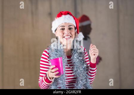 Junge casual multiethnischen Geschäft paar Spaß beim feiern das neue Jahr Partei in unfertigen startup Office mit einer grauen Wand hinter Ihnen Stockfoto