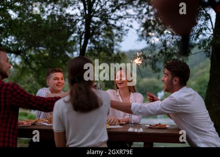 Gruppe von glücklichen Freunden mit Picknick französisch Abendessen Party im Freien Im Sommer Urlaub in der Nähe des Flusses in schöner Natur Stockfoto