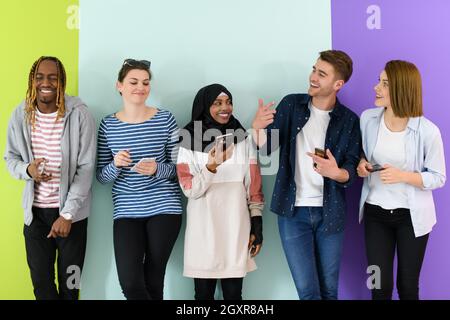Eine Gruppe verschiedener Teenager nutzt mobile Geräte, während sie sich für die Studiofotografie posieren Stockfoto