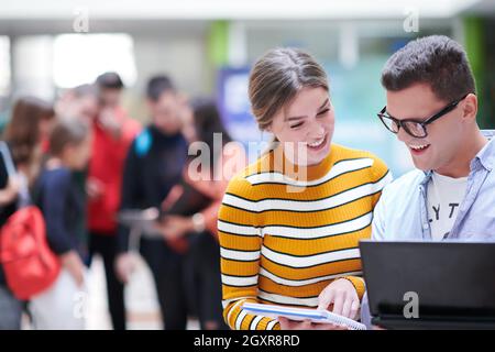 Zwei Studenten mit moderner Technik stehen dabei im Flur Warten auf den Beginn des Unterrichts Stockfoto
