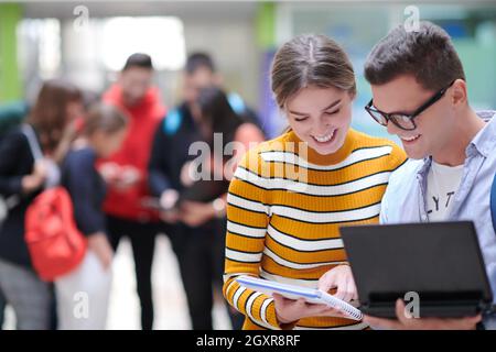 Zwei Studenten mit moderner Technik stehen dabei im Flur Warten auf den Beginn des Unterrichts Stockfoto