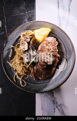 Gebratene Schweinekoteletts mit Honig-Senf-Pilzsoße und Pasta Stockfoto