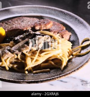 Gebratene Schweinekoteletts mit Honig-Senf-Pilzsoße und Pasta Stockfoto