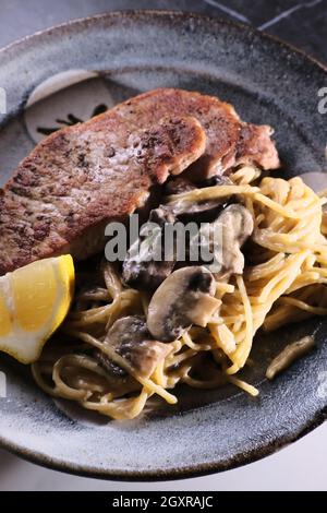 Gebratene Schweinekoteletts mit Honig-Senf-Pilzsoße und Pasta Stockfoto