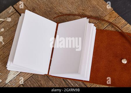 Leere Seiten eines offenen Journals mit braunem Leder auf Holzbohlen Stockfoto