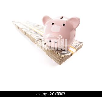 Rosa Sparschwein auf Zeile von Hunderten von Dollar-Stacks, Isolated on White Background. Stockfoto