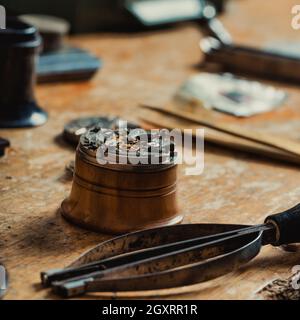 Altes Uhrwerk und Handwerkzeug auf einer Uhrmacherbank in einer Vintage-Werkstatt mit Fokus auf die Messingräder Stockfoto