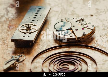 Selektiver Fokus auf Details einer Werkbank mit einem alten Uhrwerk und einer gewickelten Feder aus einer Vintage-Uhr Stockfoto