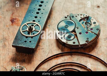 Konzentrieren Sie sich auf den geöffneten Mechanismus einer alten Uhr, auf der die Juwelen oder Rubine mit zerlegten Zahnrädern, Rädern und Feder auf einer Uhrmacherwerkbank gezeigt werden Stockfoto