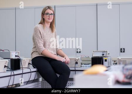 Portrait von schönen jungen weiblichen Kursteilnehmer sitzen auf dem Tisch bei Elektronik Labor Klassenzimmer Stockfoto