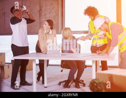 Jungen multiethnischen Business Team Dokumente prüfen und Business Workflow auf der Baustelle unter Verwendung der Virtual reality Headset und Laptop wi Stockfoto