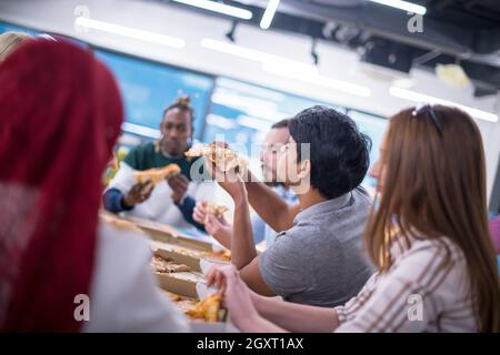 Freundlich diverse multiethnischen Business Team Essen teilen Pizza zusammen im Startup office, multirassischen Mitarbeiter Mitarbeiter Gruppe genießen Pause sprechen. l Stockfoto